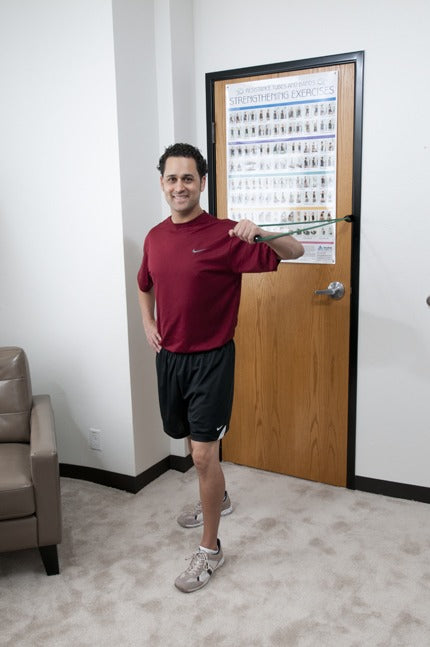 Person working out in a room with a 3 ft. Unilateral Loop with Handle Green Medium Resistance attached to a door standing in room